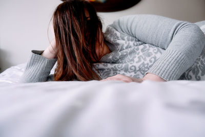 Midsection of woman lying on bed at home