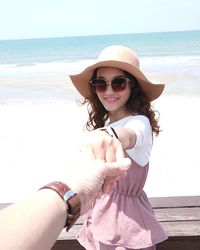 Young woman wearing sunglasses at beach against sky