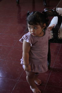 Cute girl looking down while standing on tiled floor