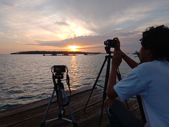 Rear view of man photographing against sky