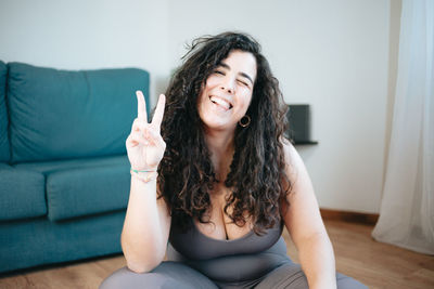 Portrait of young woman gesturing while sitting at home
