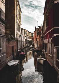 Canal amidst buildings in city against sky