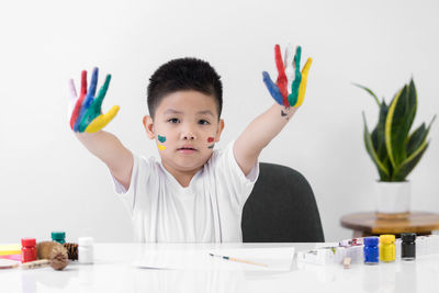 Portrait of boy holding multi colored pencils on table