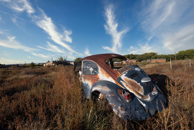 Panoramic view of abandoned car on field against sky