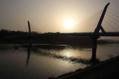 Bridge over river at sunset