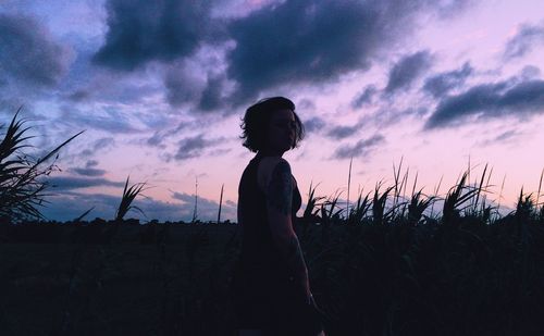 Portrait of woman standing on field against sky during sunset