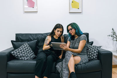 Two businesswomen use a tablet in the office break