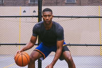 Young man playing basketball against chainlink fence