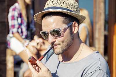 Young hiker lights his pipe in front of the hut