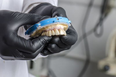 Midsection of dentist working on dentures at clinic