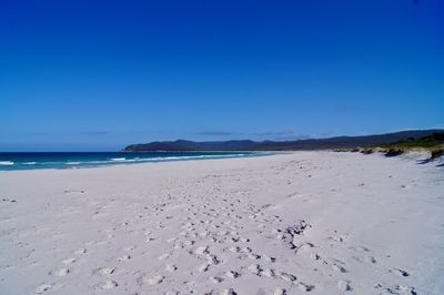 Scenic view of beach against clear blue sky