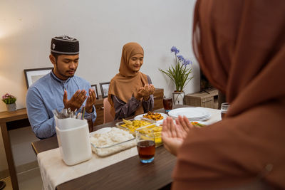 Smiling couple praying before having dinner