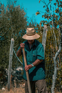 Man holding hat standing by plants