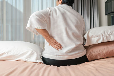 Rear view of man sitting on bed