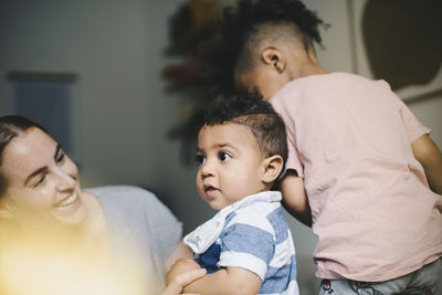 Smiling mother playing with sons at home