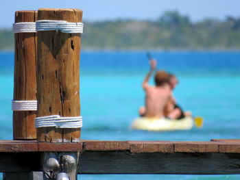 Close-up pier with people in a canoe in background