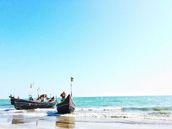 People on beach against clear blue sky