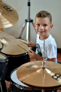 Portrait of boy smiling while playing drums