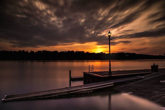 sunset, water, sky, cloud - sky, tranquility, tranquil scene, lake, scenics, beauty in nature, reflection, silhouette, pier, nature, cloudy, idyllic, cloud, orange color, street light, river, railing