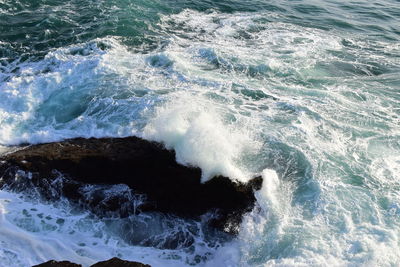 High angle view of waves splashing on rocks