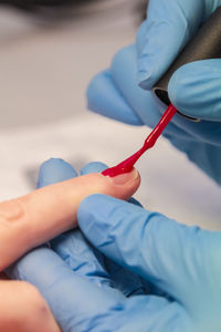 Close-up of a woman applying red nail polish. women's beauty service