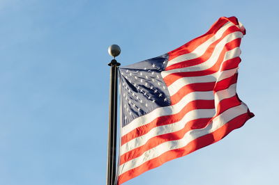 Low angle view of flags against clear blue sky