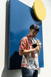 Full length of young man holding blue wall