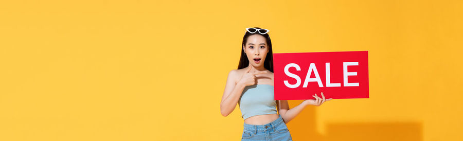 Woman standing against yellow background