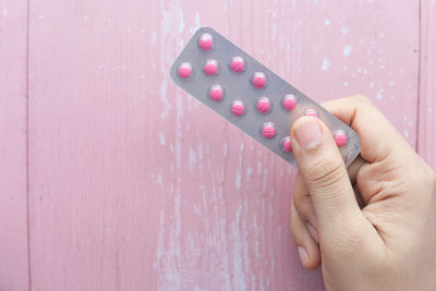 Close-up of woman hand holding pink wall