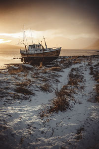 Norwegian wooden boat beached at sunset with snow