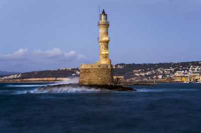 Lighthouse by building against sky in city