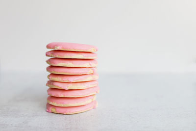 Stack of sugar cookies with pink frosting on gray table