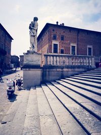 Statue on street amidst buildings in city against sky