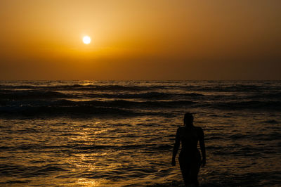 Silhouette man standing at beach during sunset