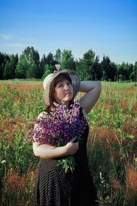 Young woman standing by purple flowers on field