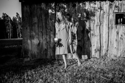 Girl standing on field against hut