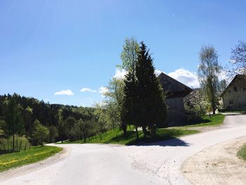 Road leading towards mountains against clear blue sky