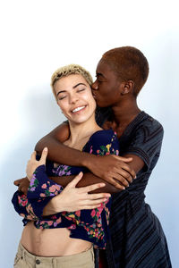 Portrait of smiling lesbian couple embracing against white background