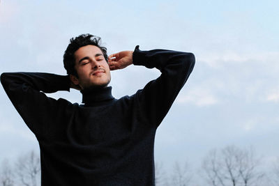 Portrait of young man standing against sky