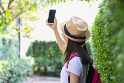 Rear view of woman photographing over mobile phone