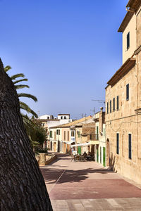 Street amidst buildings against clear blue sky