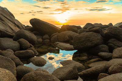 Rocks in sea during sunset