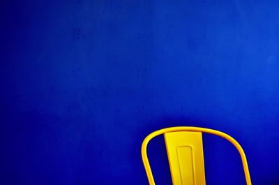 Close-up of yellow chair against blue wall
