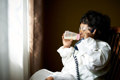 Girl drinking milk while talking on telephone at home