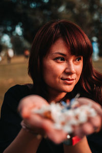 Close-up of woman holding flowers looking away