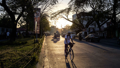 Men walking on bicycle in city against sky