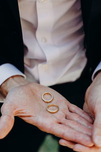 Midsection of bridegroom holding wedding rings