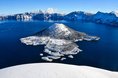 Frozen sea against mountain during winter