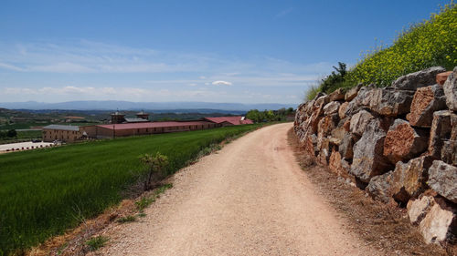 Road amidst field against sky