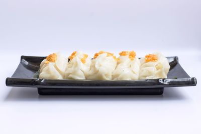Close-up of bread in plate on table against white background